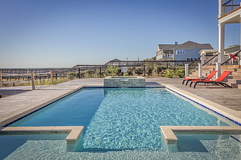 Outdoor swimming pool with ocean view and lounge chairs
