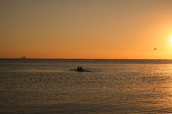Silhouette of Two Rowers on Calm Sea at Golden Sunset
