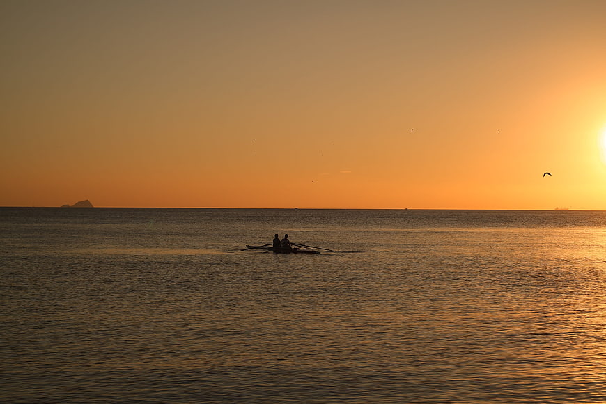 Silhouette of Two Rowers on Calm Sea at Golden Sunset