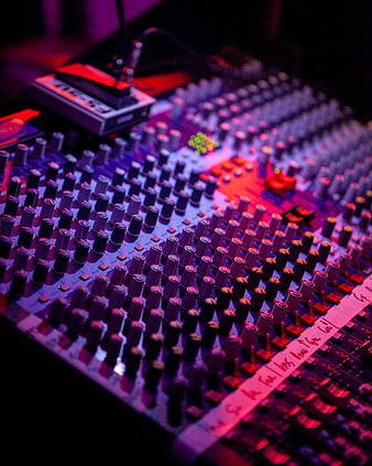 Close-up of DJ mixing console with colorful stage lighting
