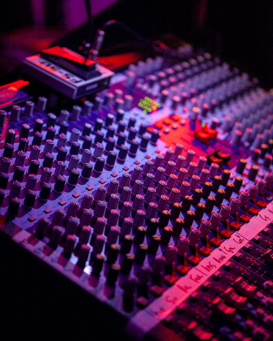 Close-up of DJ mixing console with colorful stage lighting