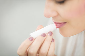 Woman applying lip balm close-up with manicured nails