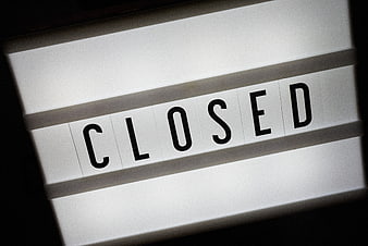 Close-up of a white flip sign displaying the word CLOSED in black letters