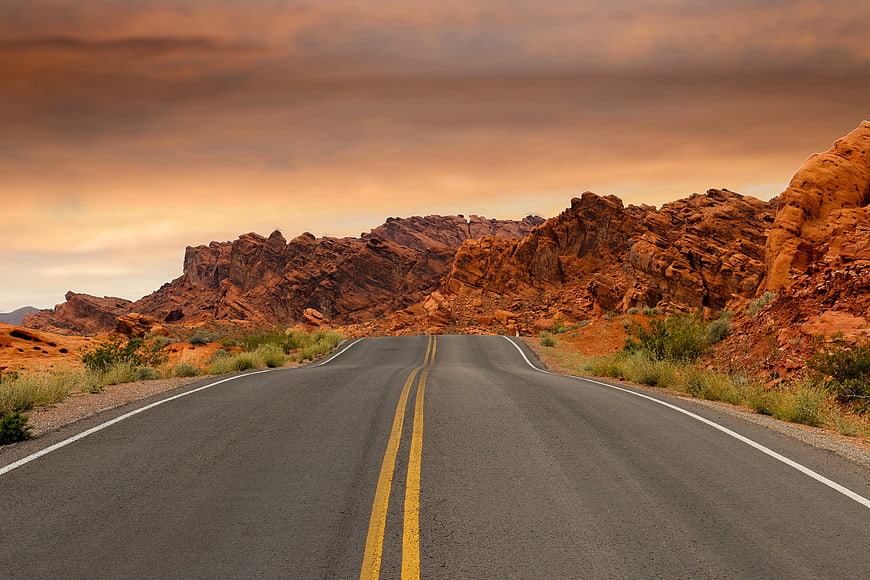 Desert Highway Leading to Red Rock Mountains at Sunset