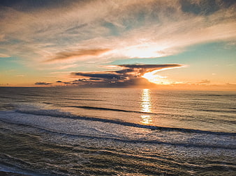 Dramatic Sunset Over Ocean with Golden Light and Clouds