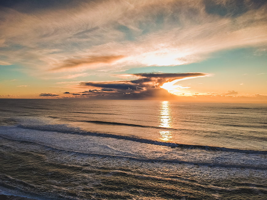 Dramatic Sunset Over Ocean with Golden Light and Clouds