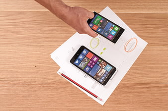 Top view of smartphones on design sketches and wooden desk