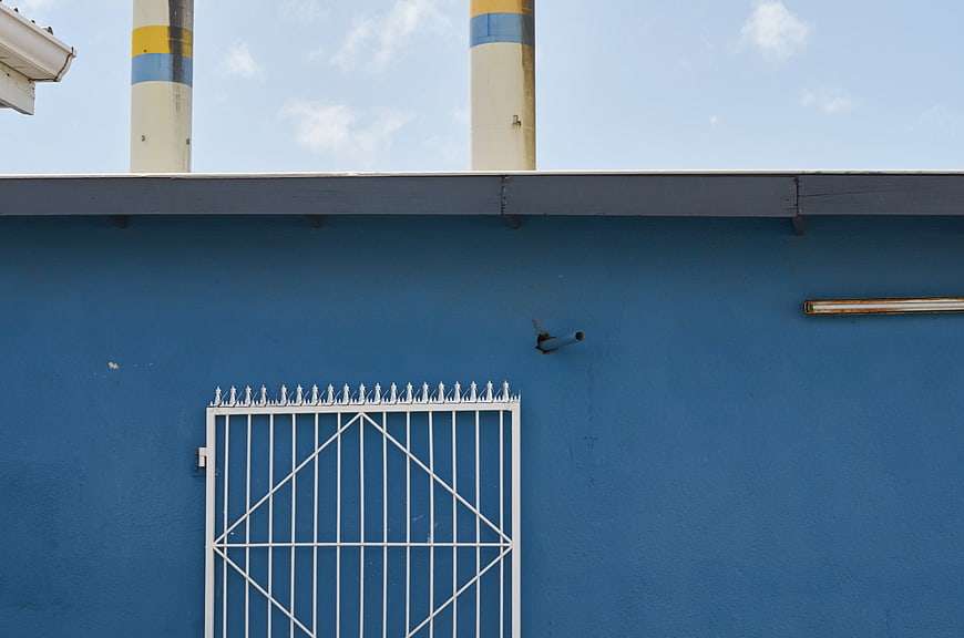 Blue industrial wall with white metal gate and smokestacks