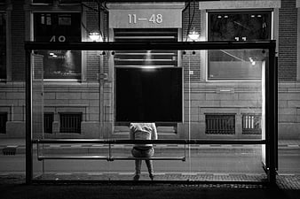 Lone figure waiting at a bus stop at night