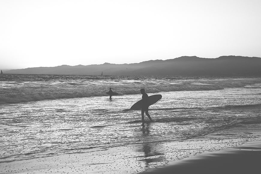 Silhouette of Surfers Walking on Beach in Black and White
