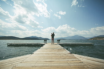 Father holding child on wooden pier overlooking lake
