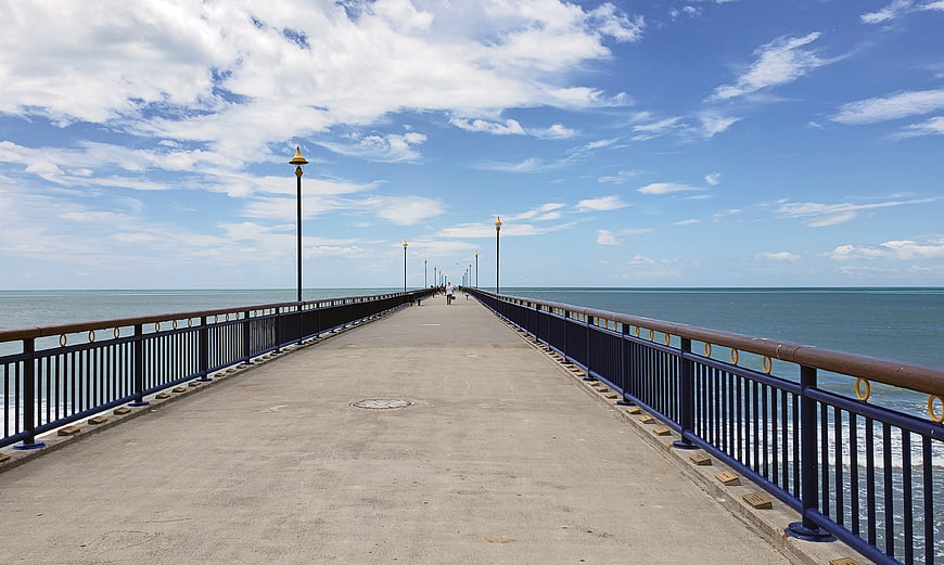 Long pier extending into the ocean under a blue sky