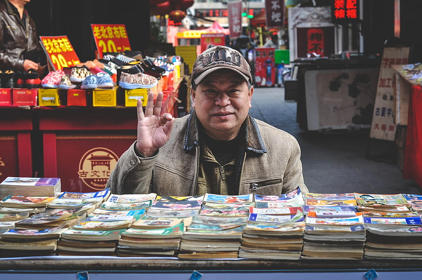 Friendly Chinese Vendor Selling Books at Street Market