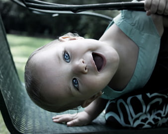 Close-up of happy baby girl with blue eyes smiling upside down