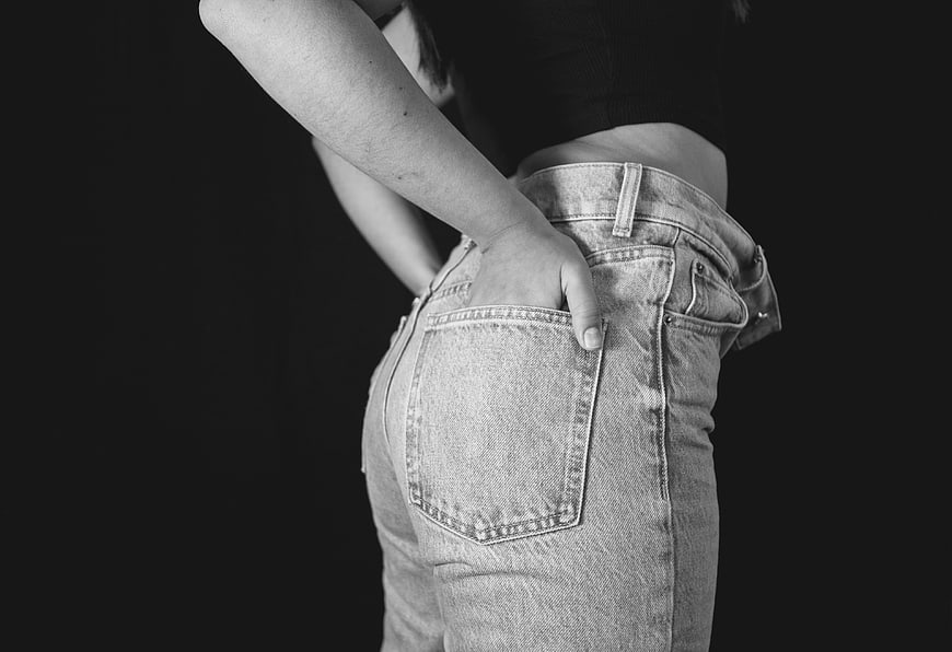 Black and white photo of woman in jeans with hand in pocket