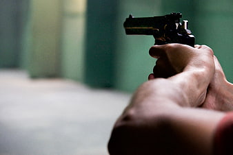 Close-up of hands aiming a black pistol at a shooting range