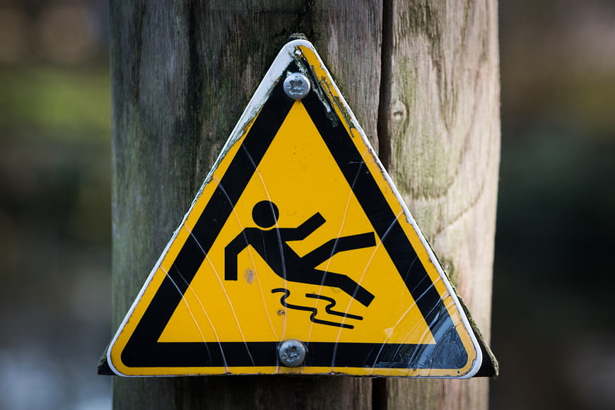 Yellow slippery when wet warning sign on wooden post