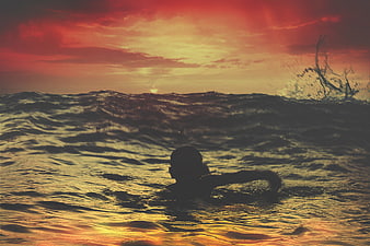 Silhouette of Child Swimming in Ocean at Sunset