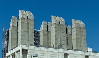 Concrete ventilation towers on urban rooftop against blue sky