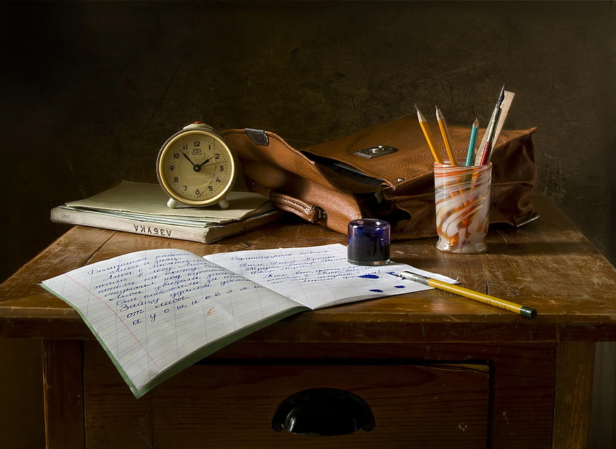 Vintage wooden desk with open notebook, ink, and school supplies