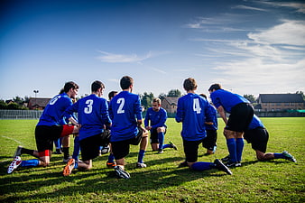 Soccer Team Huddle Kneeling on Grass Field