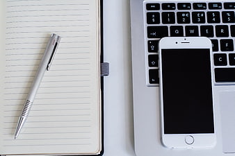 Flat lay of notebook, pen, laptop, and smartphone workspace