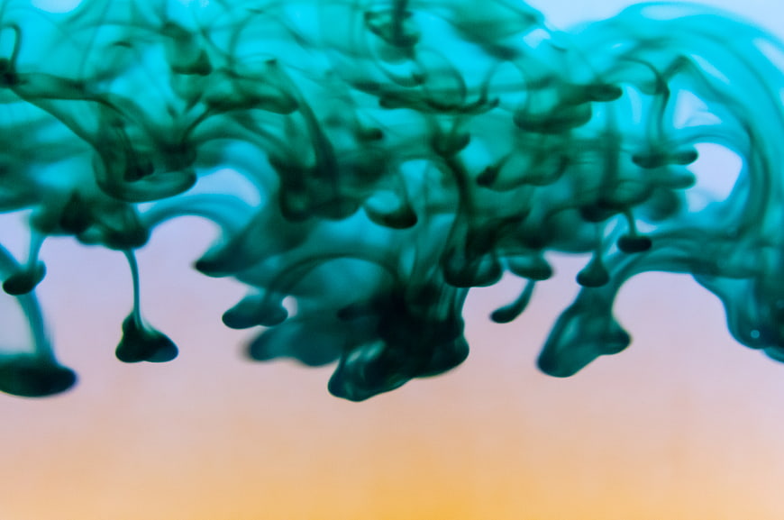 Abstract teal ink swirling in water with gradient background