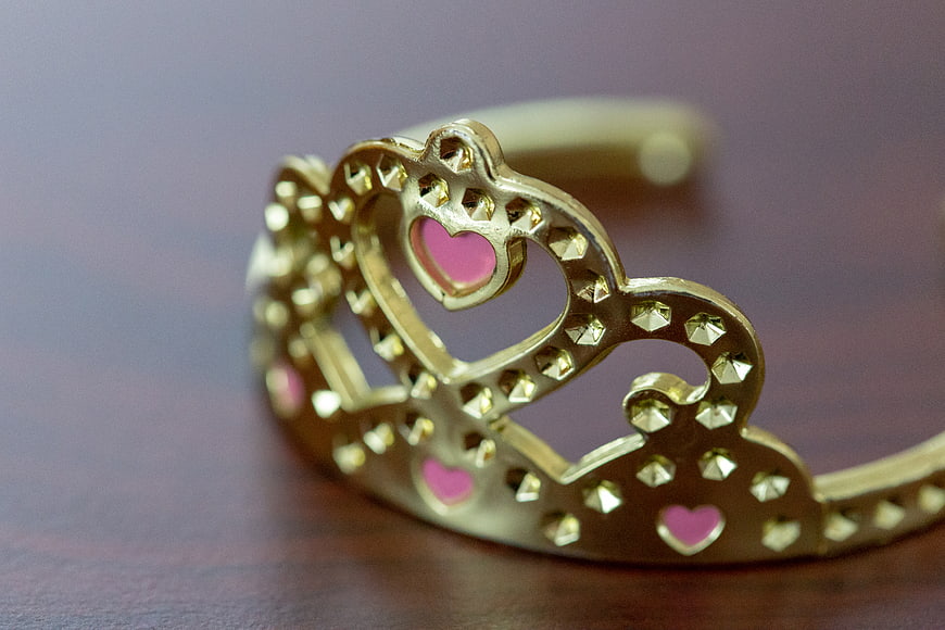 Gold Princess Tiara with Pink Hearts on Wooden Surface