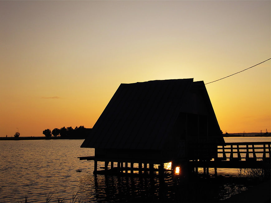 Silhouette of wooden pier house at sunset over calm lake