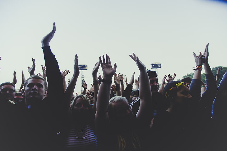 Silhouetted crowd with raised hands at outdoor concert