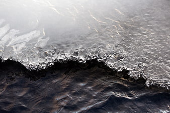 Close-up of melting ice edge on dark flowing water