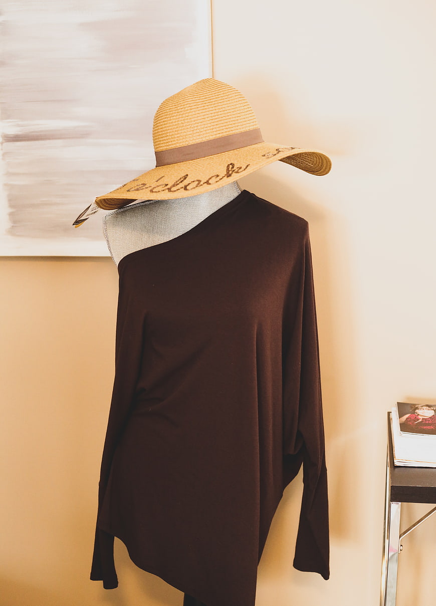 Straw sun hat and brown sweater on mannequin