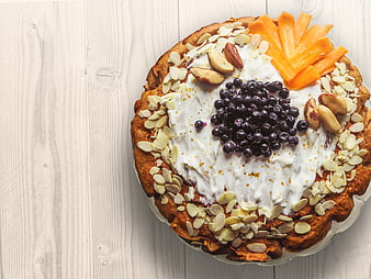 Overhead view of carrot cake with cream, blueberries, and almonds