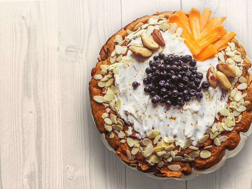 Overhead view of carrot cake with cream, blueberries, and almonds
