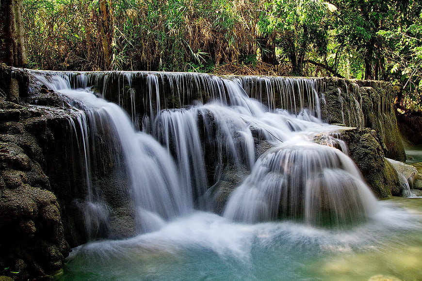 Serene Waterfall Flowing Over Rocks in Lush Forest
