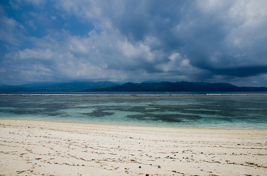 Tropical Beach with Dramatic Clouds and Distant Mountains