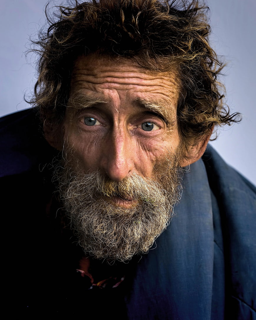 Close-up portrait of elderly man with wild curly hair and beard