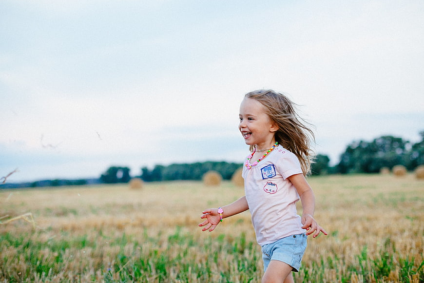 Happy little girl running through a golden wheat field