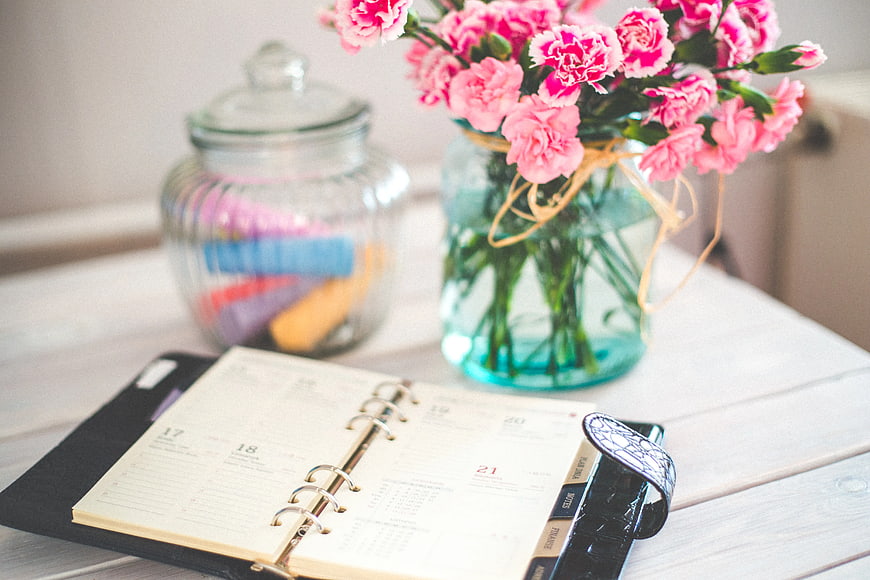 Pink Carnations and Planner on White Desk
