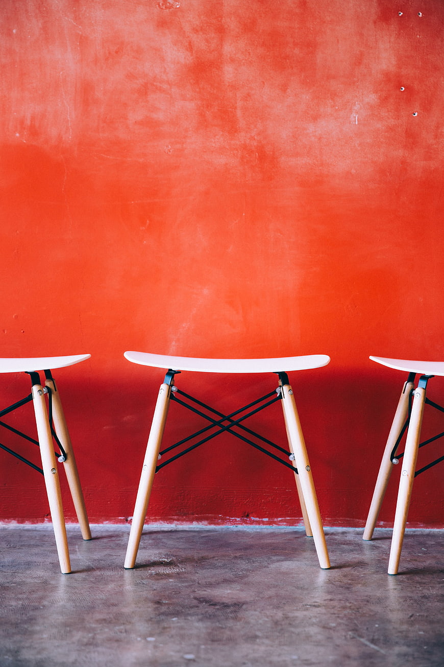 Modern White Stools Against Vibrant Red Textured Wall