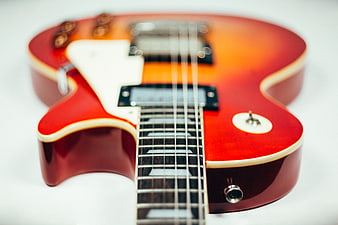 Close-up of a red sunburst electric guitar on white background