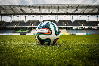 Soccer Ball on Green Grass in Empty Stadium