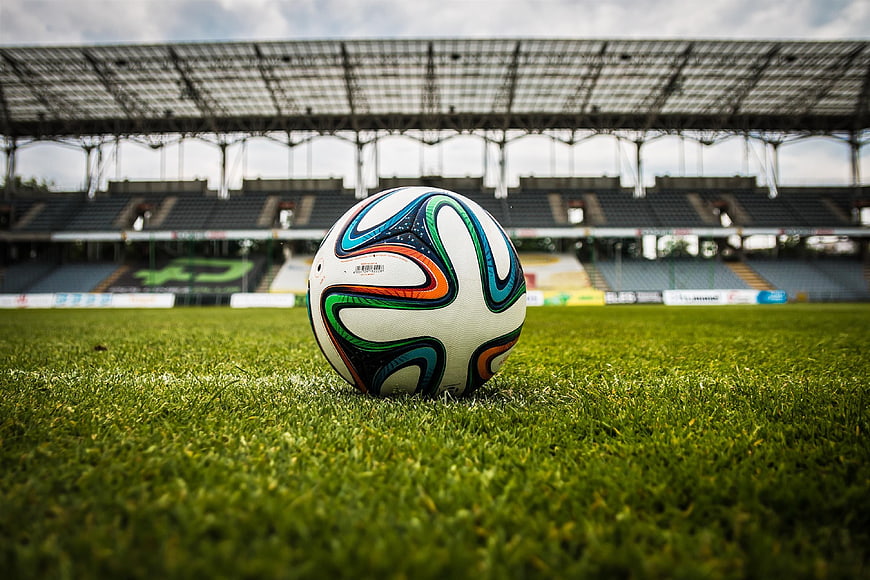Soccer Ball on Green Grass in Empty Stadium