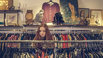 Young woman browsing clothes in vintage thrift store