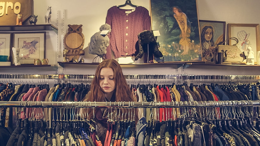 Young woman browsing clothes in vintage thrift store