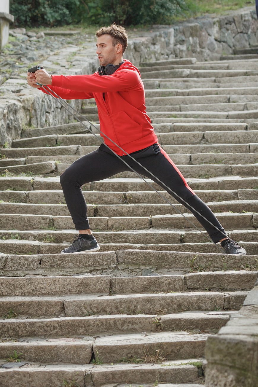 Athletic Man Exercising with Resistance Bands on Stone Stairs