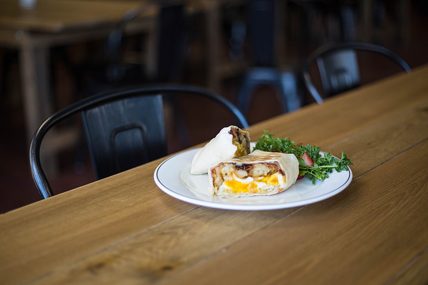 Grilled breakfast wrap on wooden table in cafe