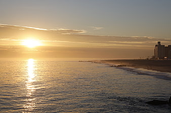 Golden Sunset Over Ocean Beach With City Skyline