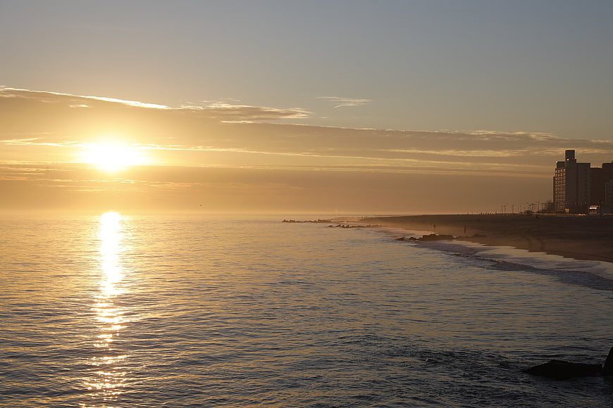 Golden Sunset Over Ocean Beach With City Skyline