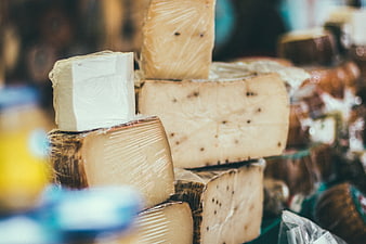 Assorted artisanal cheese blocks wrapped in plastic at market